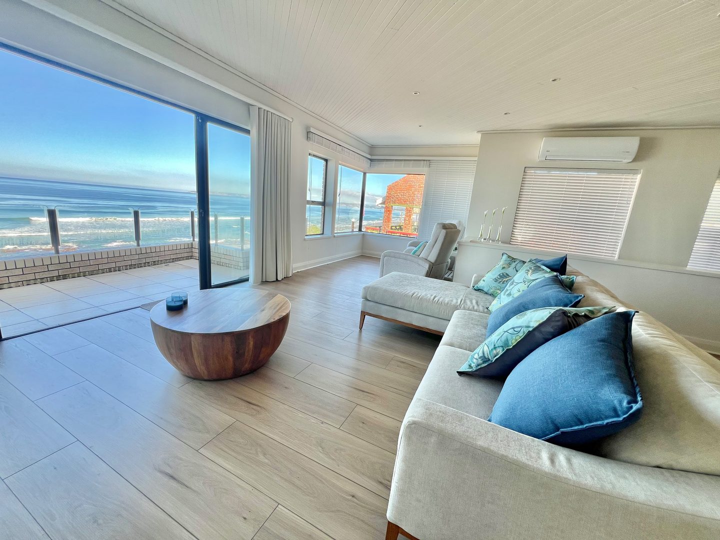 The sea filling the glass wall of the top lounge at 431 Kusweg, doors open to the balcony